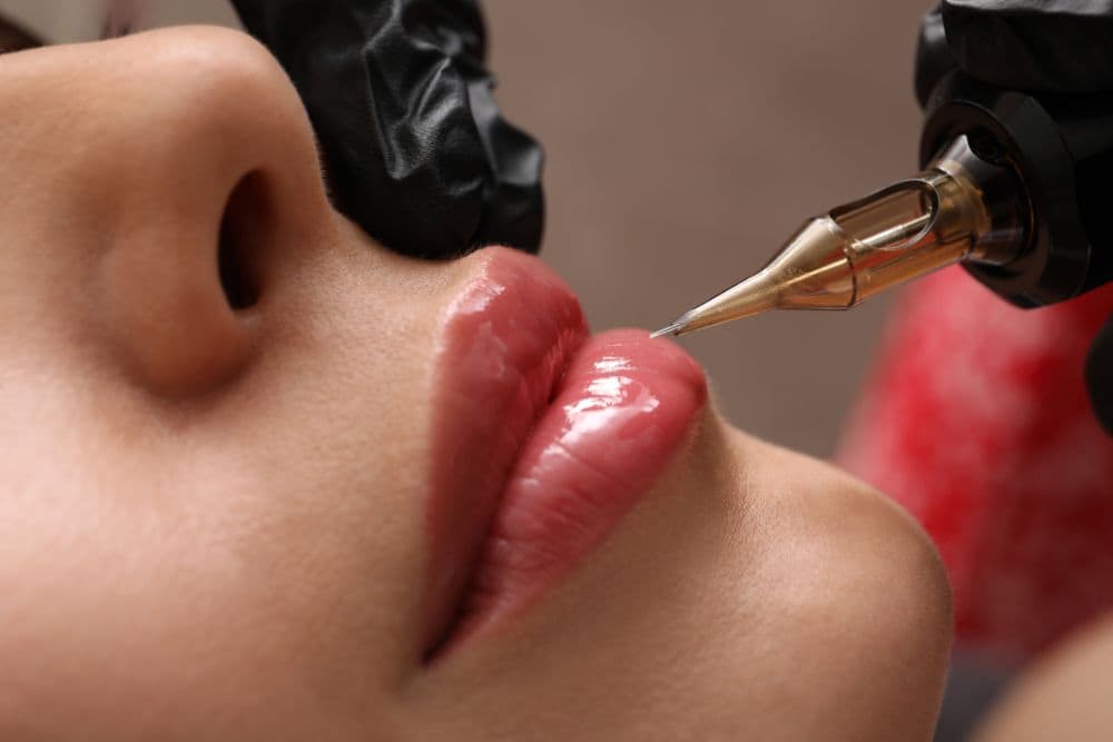 A person's mouth receiving a cosmetic procedure, likely semi-permanent makeup or lip tattooing